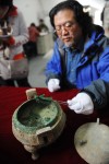 Archaeologist Liu Daiyun picks up a piece of bone from bronze tripod vessel