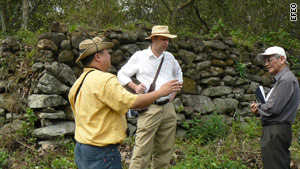 Andrew Hardy (center) and Nguyen Tien Dong (left) in front of wall