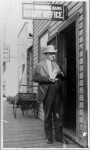 Judge Wickersham in front of First National Bank Assay Office holding a giant brick of gold