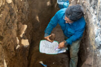 Archaeologist examines pottery vessel found in the grave. Photo courtesy National Directorate of Cultural Heritage.